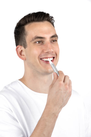 A hand holding a BioLight Teeth Whitening Gel Pen, demonstrating how to apply the gel for effective whitening.
